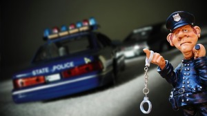 statuette cop with handcuffs and state trooper car in background