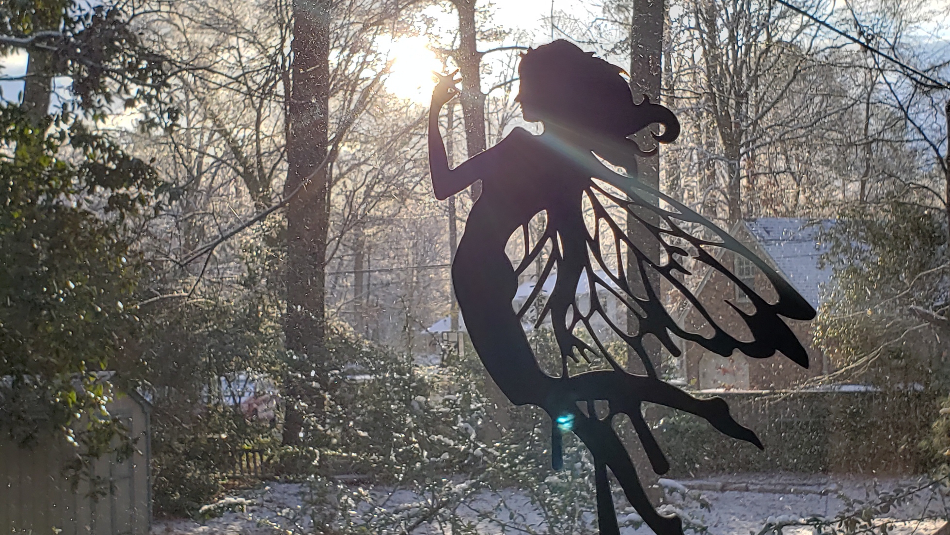 pic of fairy carving in window with backdrop of snowy yard